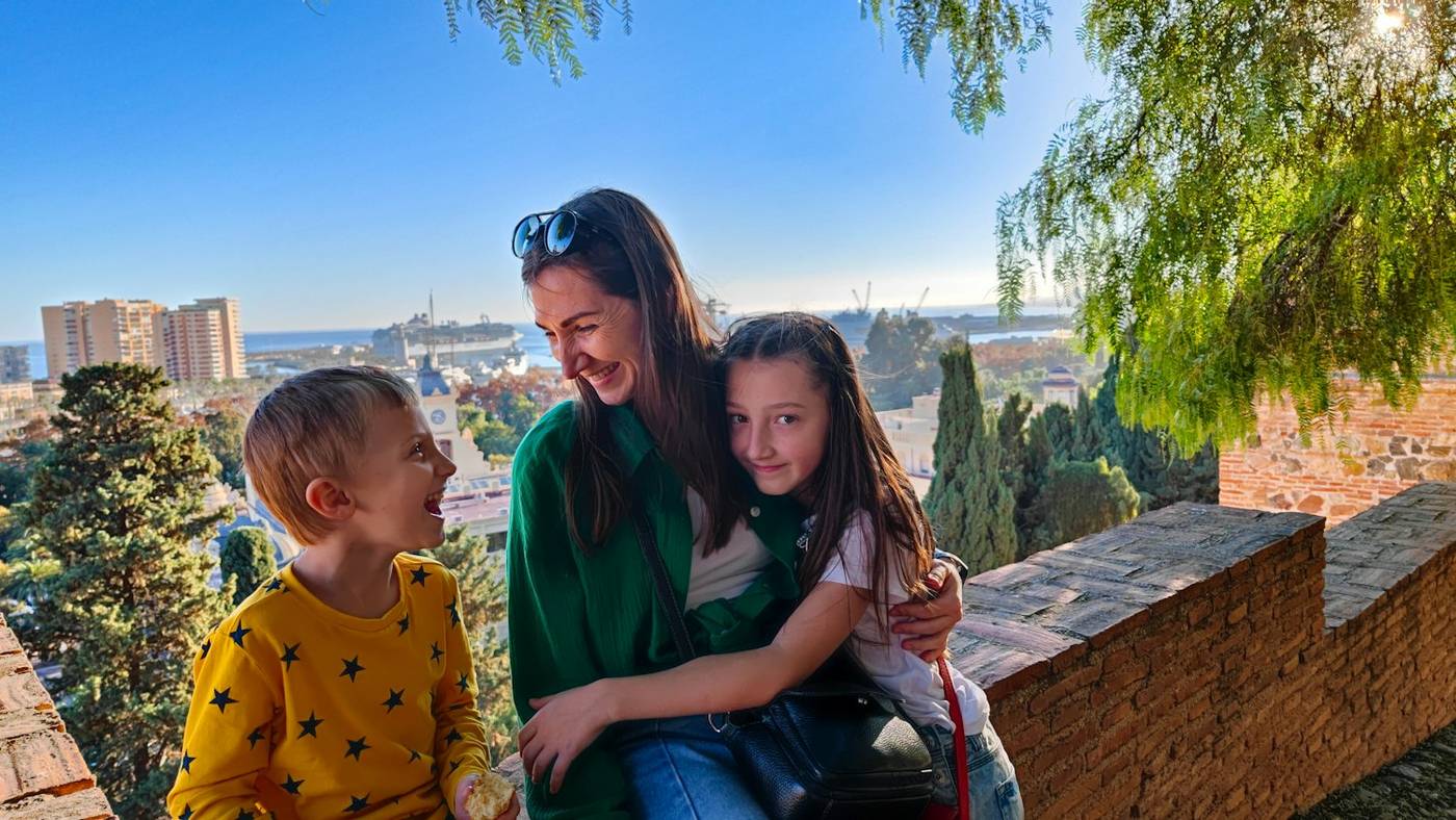 Mother hugging her two children on a sunny terrace in Spain